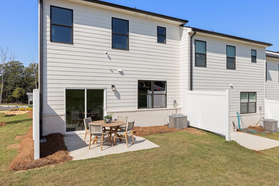 A house with a patio and a table and chairs in the front.