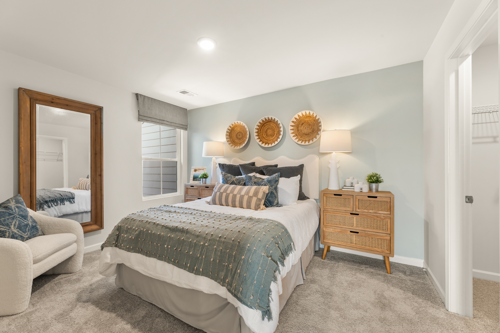 A bedroom with a bed and a mirror.