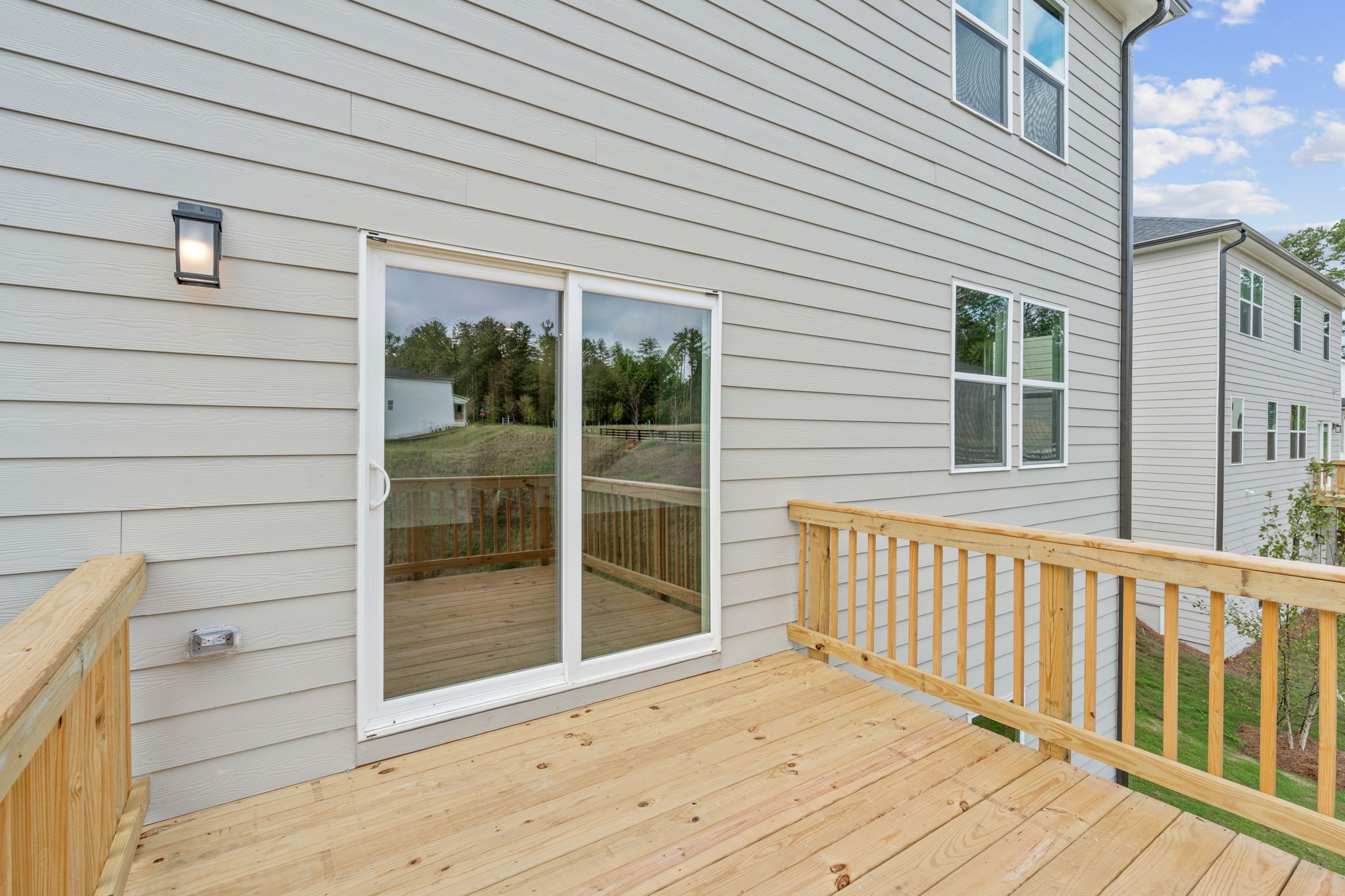 A deck with a railing and a door leading to a house.
