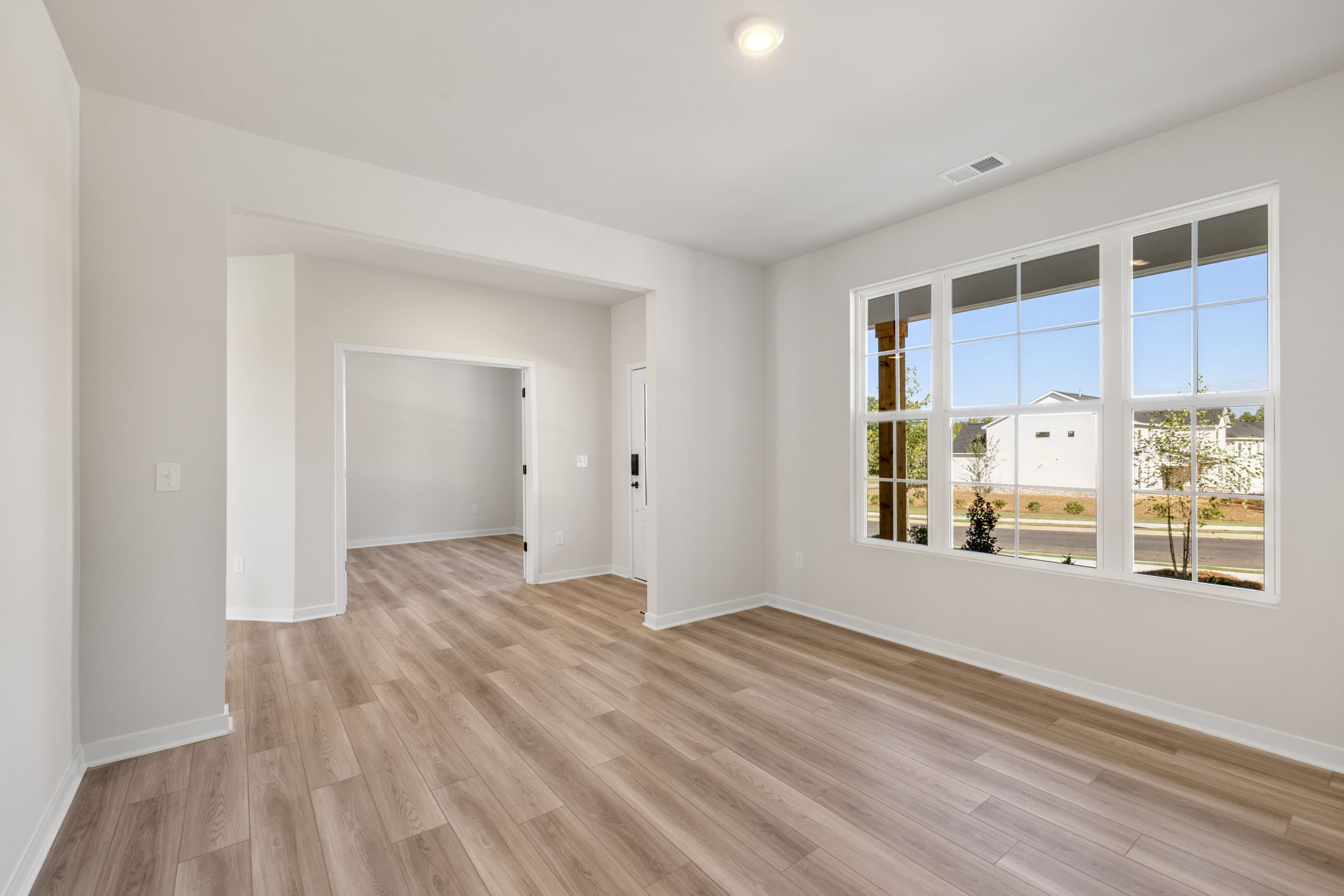 A room with a wood floor and a window with a view of the city.