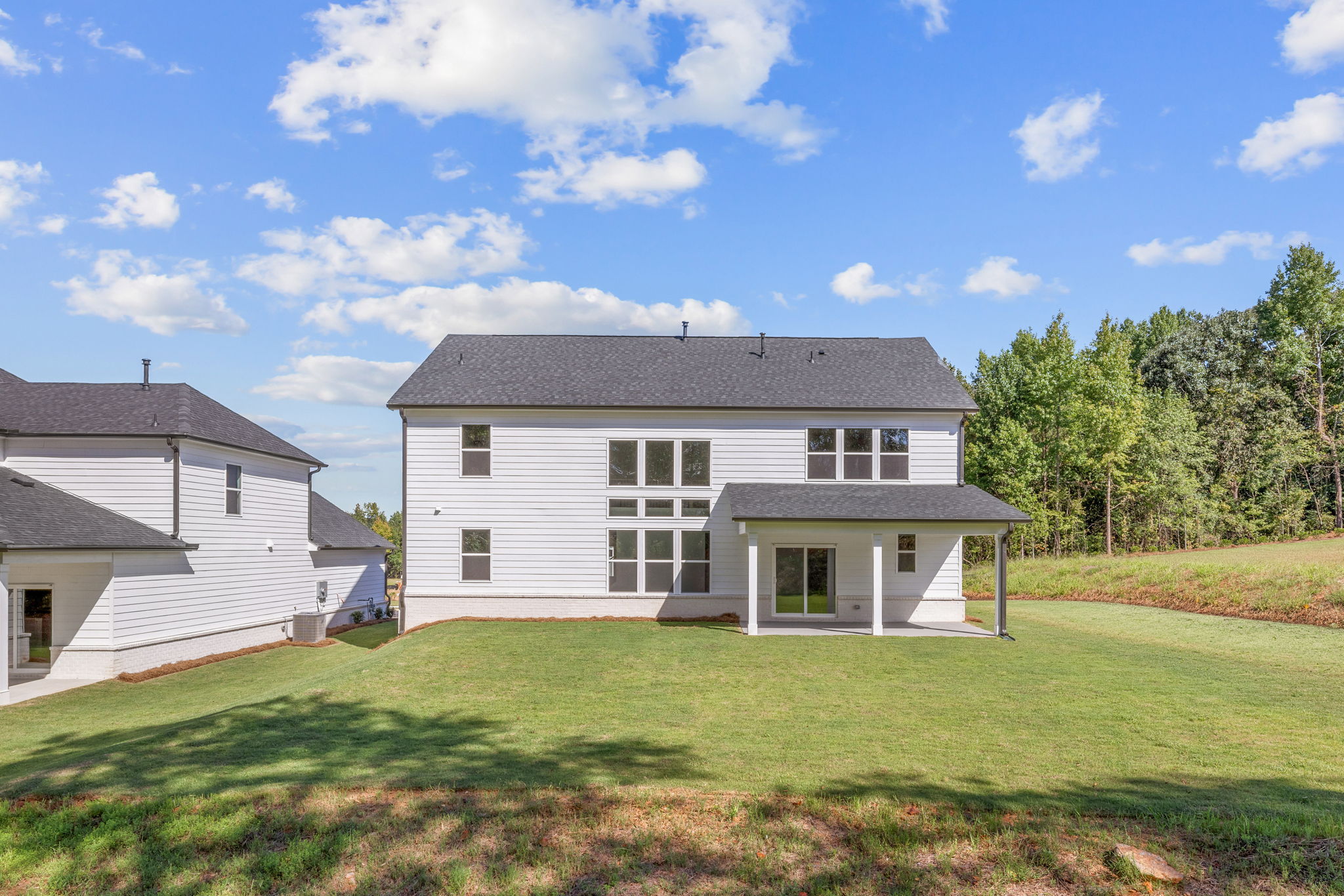 A house with a lawn and trees in the back.
