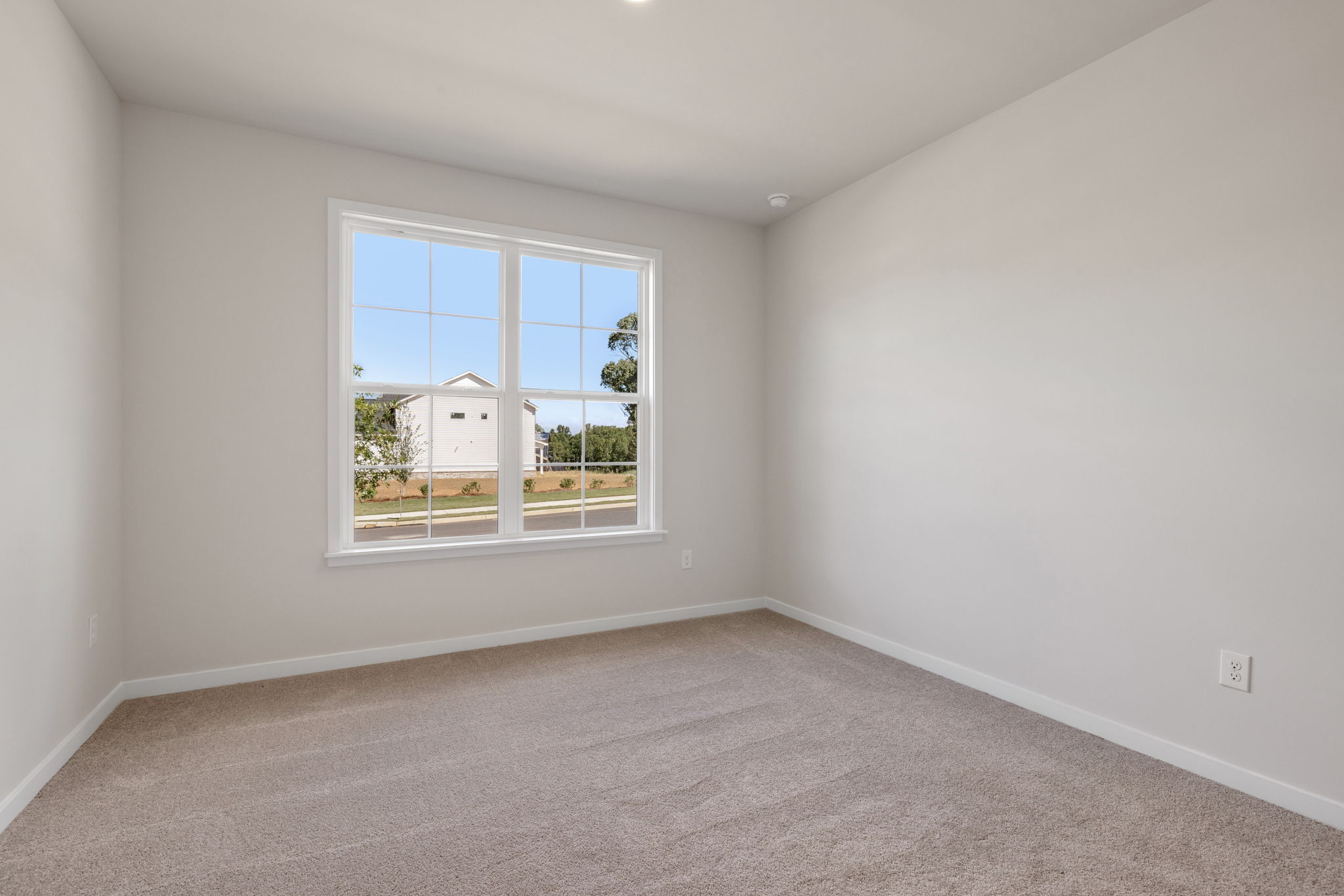 A room with a window and a white wall.