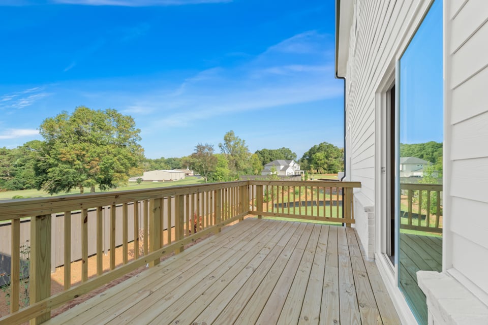 A wooden deck with a railing and trees in the background.