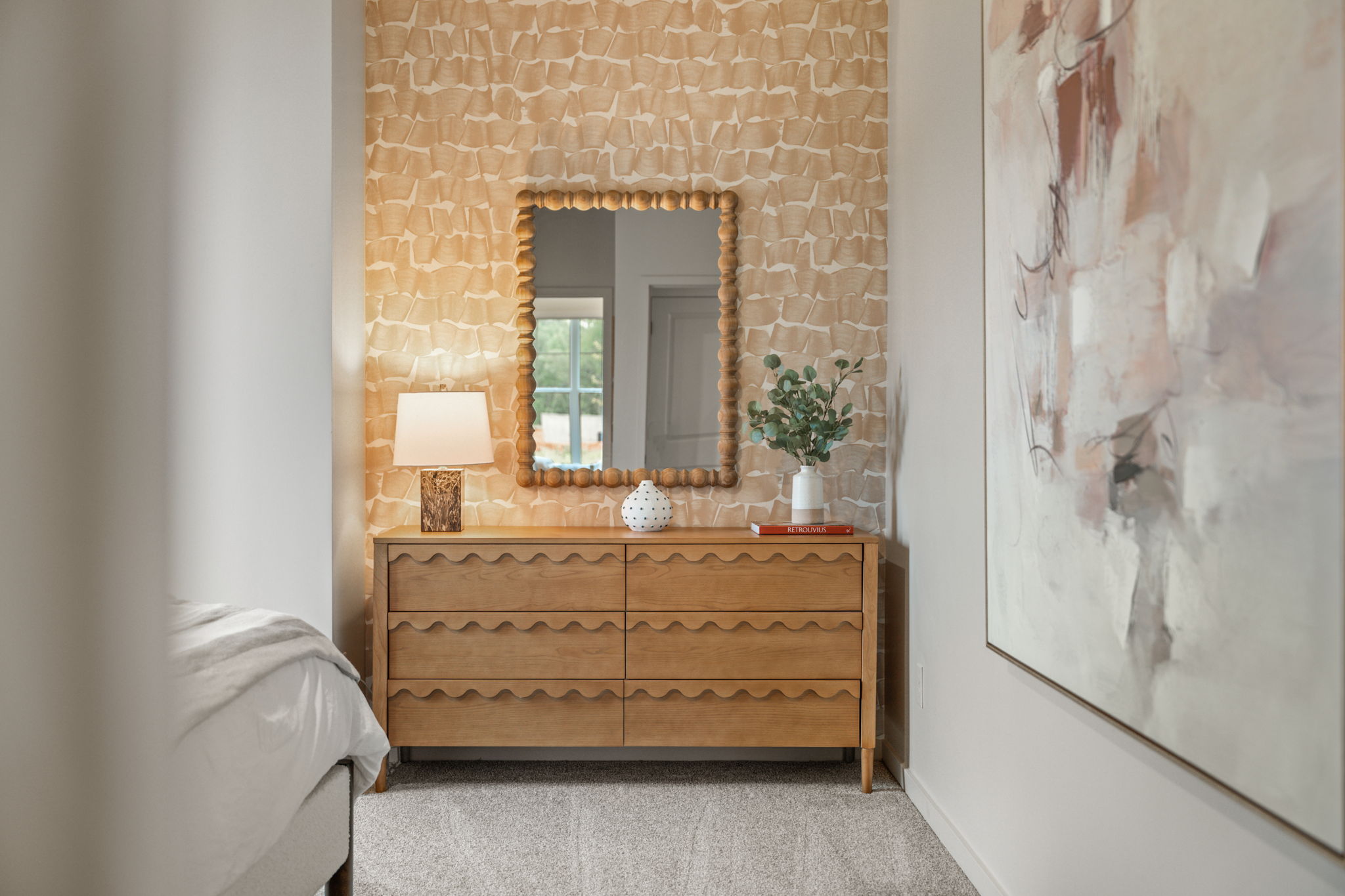 A room with a mirror and a dresser.