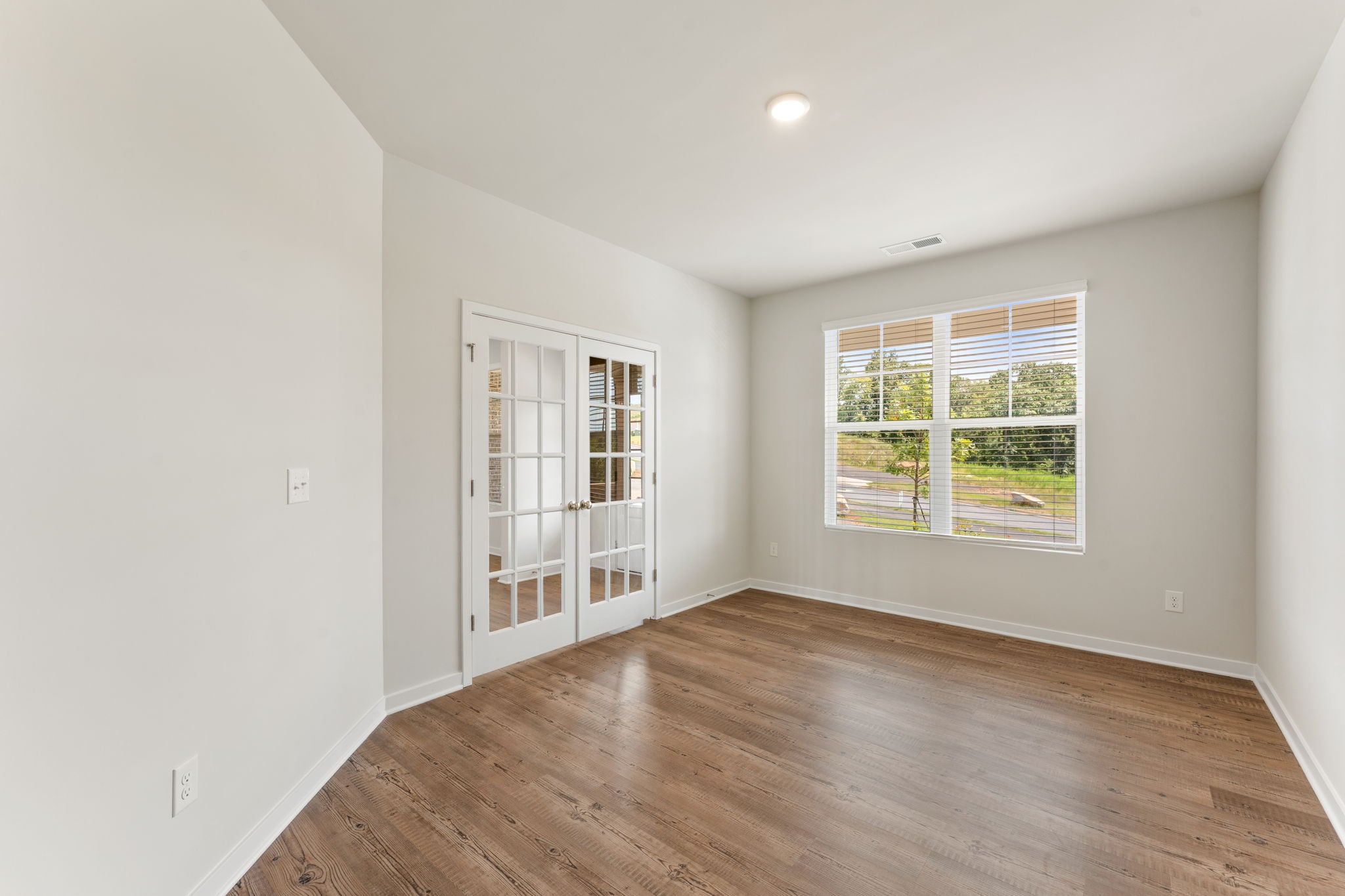 A room with a wood floor and a window with a wood floor.