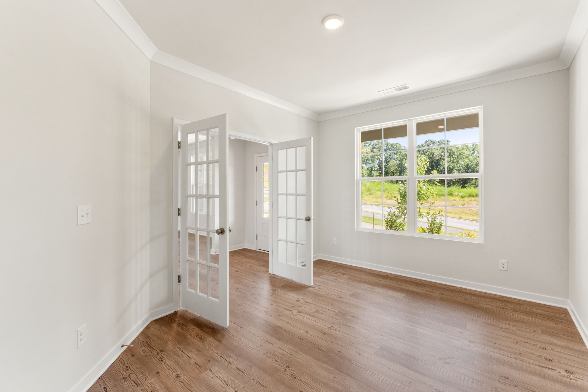 A room with a wood floor and a window with a wood floor.
