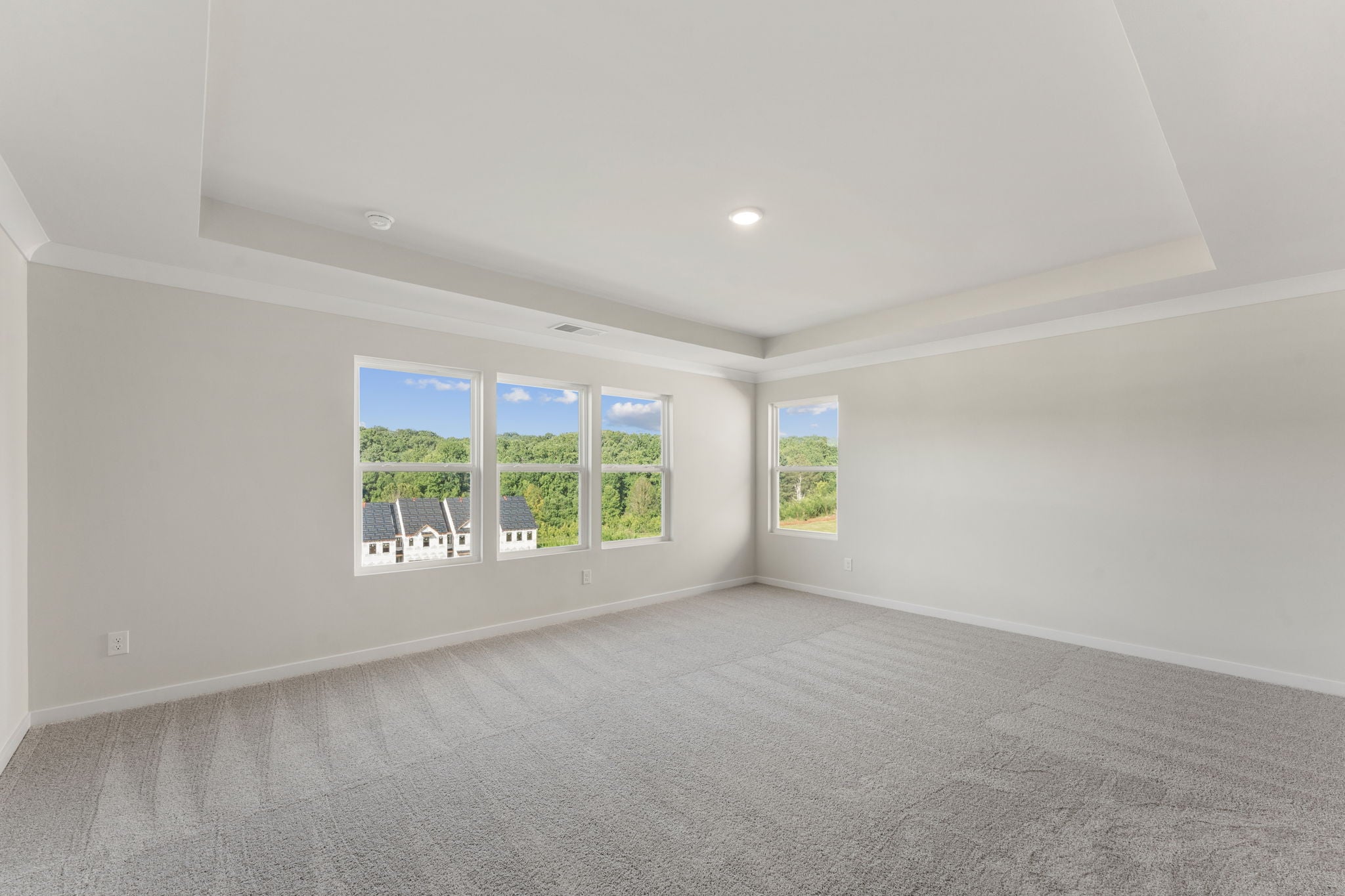 A room with a large window and a large white wall with a chair and a table and chairs.