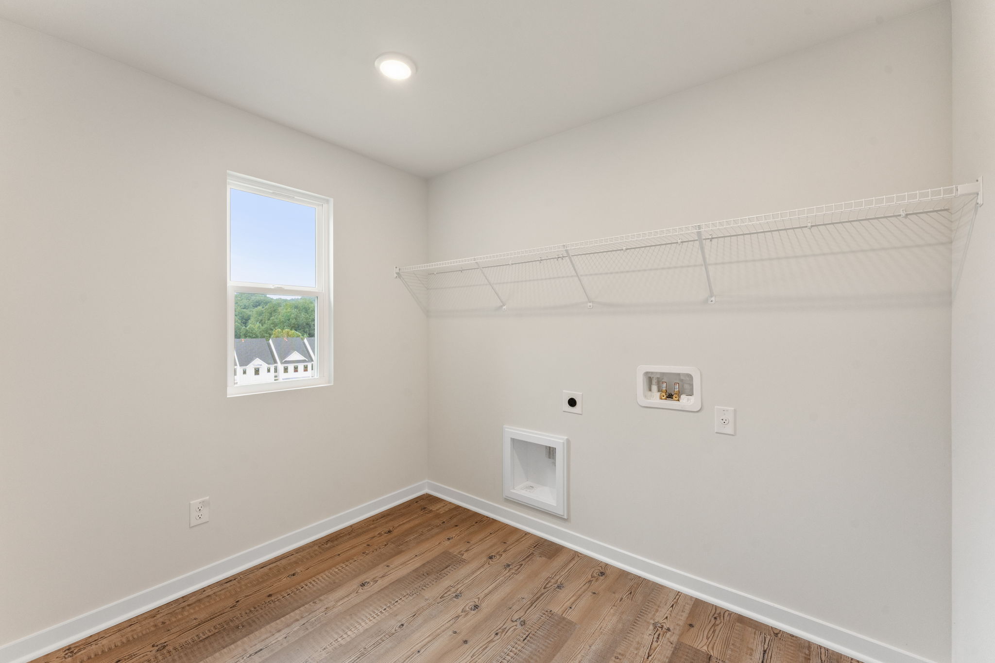 A room with a wood floor and a window with a painting on the wall.