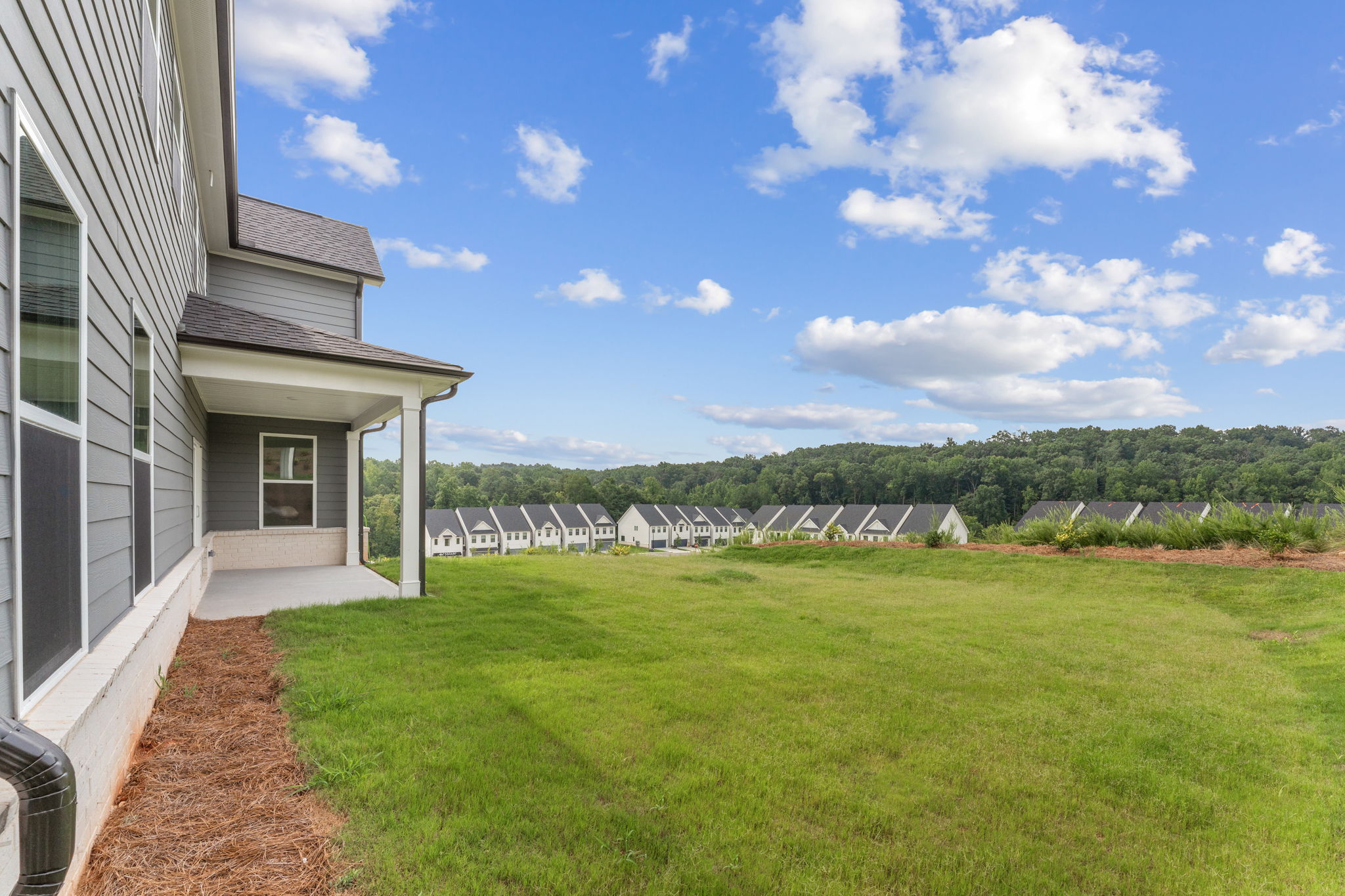 A grassy area with buildings and trees in the background.