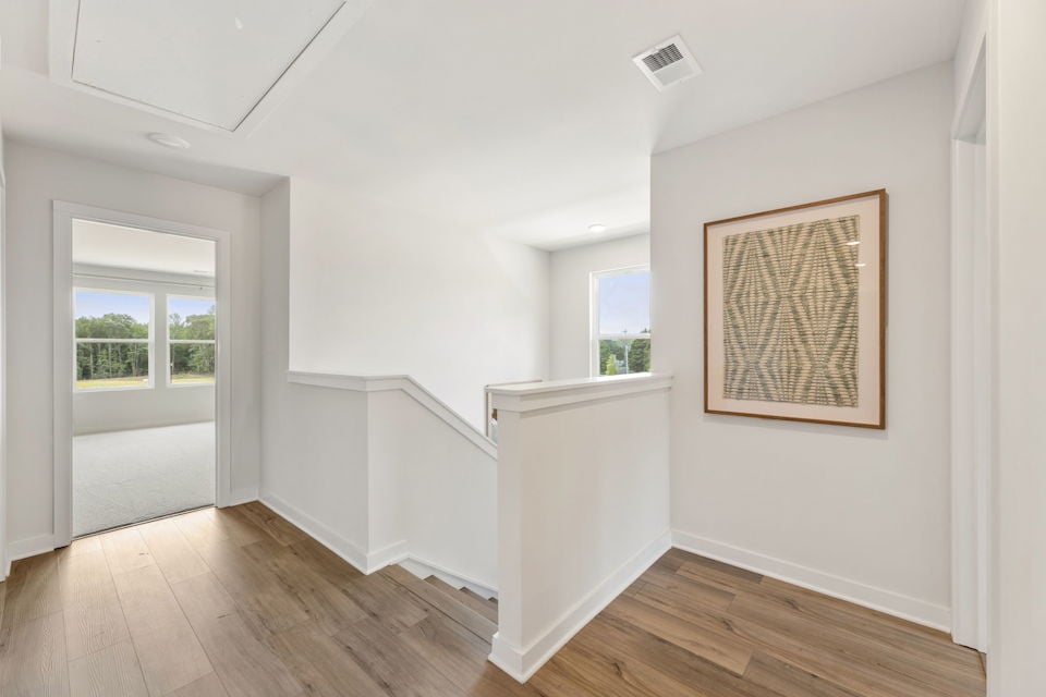 A room with a wood floor and a white wall with a painting on it.