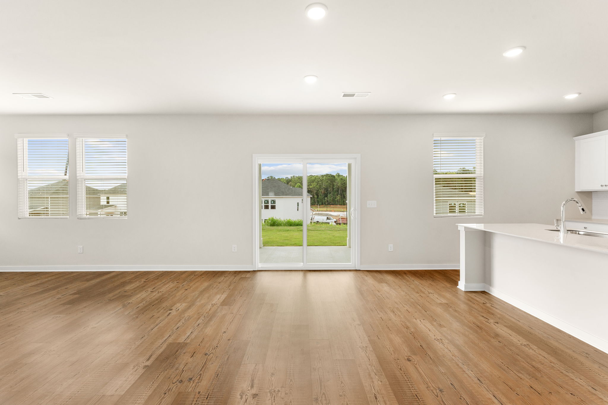 A room with a wood floor and a window with blinds.