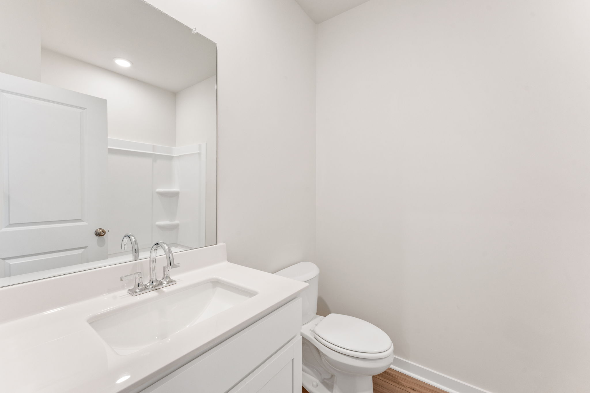 A bathroom with a sink toilet and mirror.