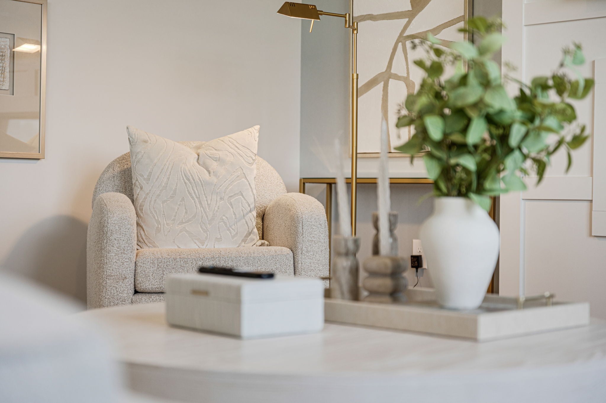 A white couch and a white vase with a plant in it.