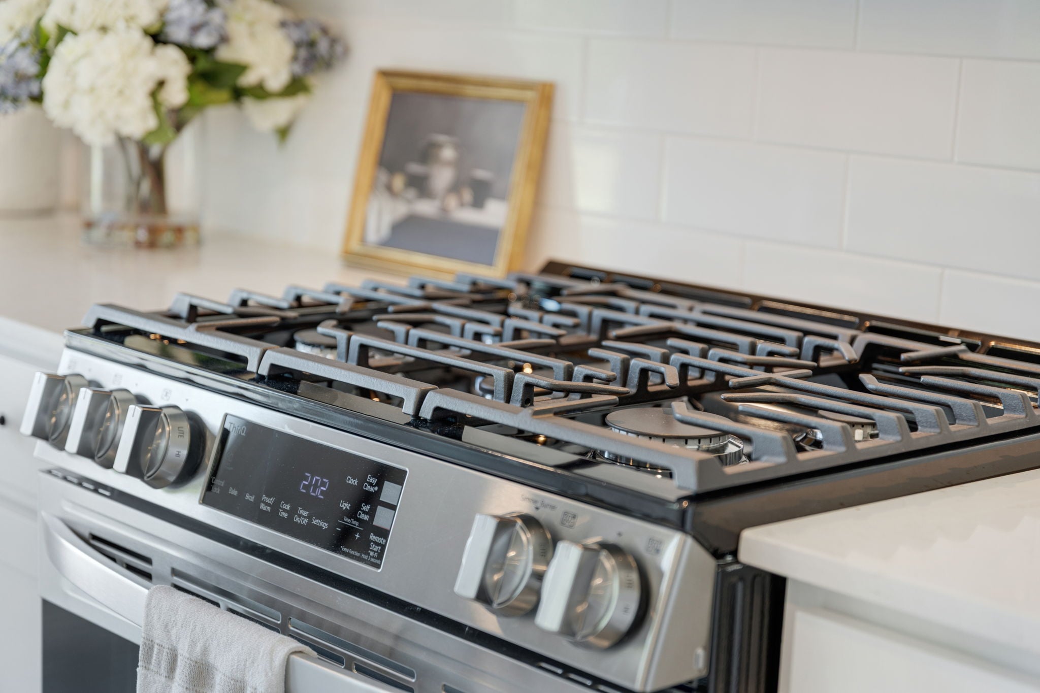 A stove top with a vase of flowers on the side.