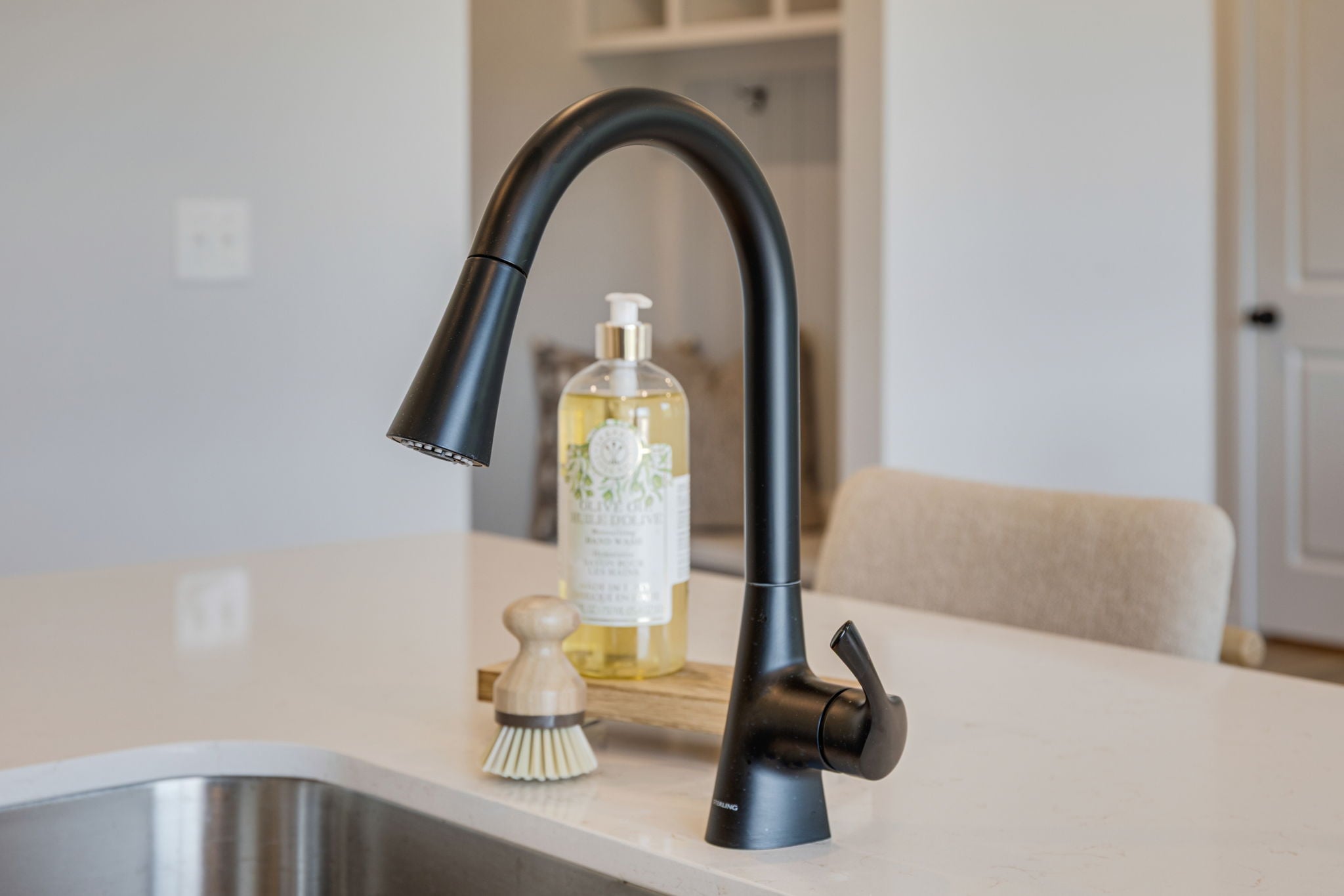 A faucet and a bottle of soap on a counter.