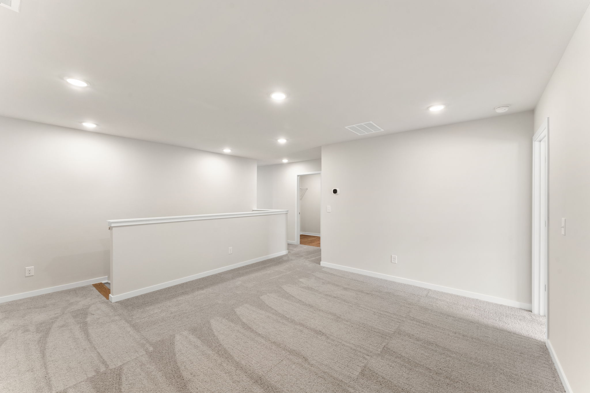 A room with a carpet and a white wall.
