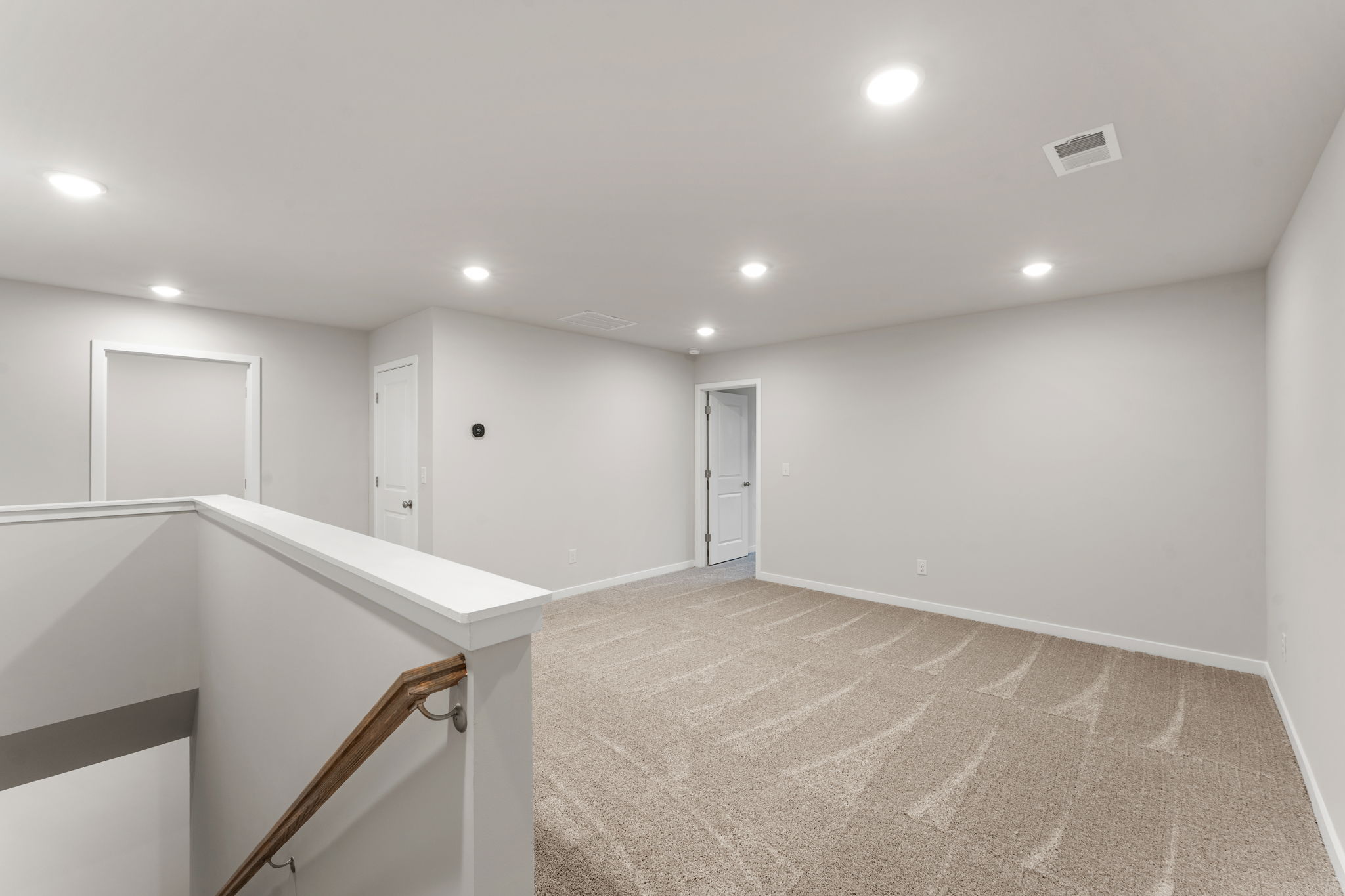 A room with a carpet and a staircase.