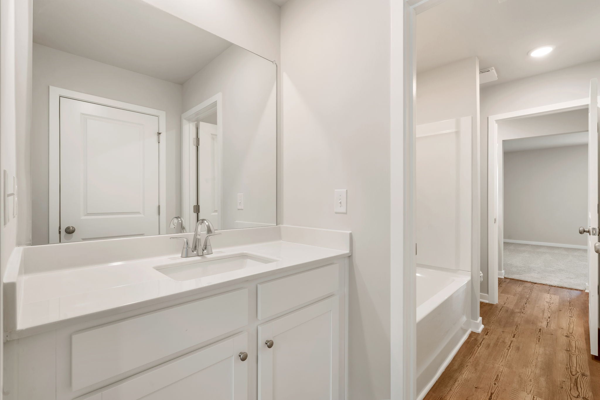 A bathroom with a tub sink and mirror.