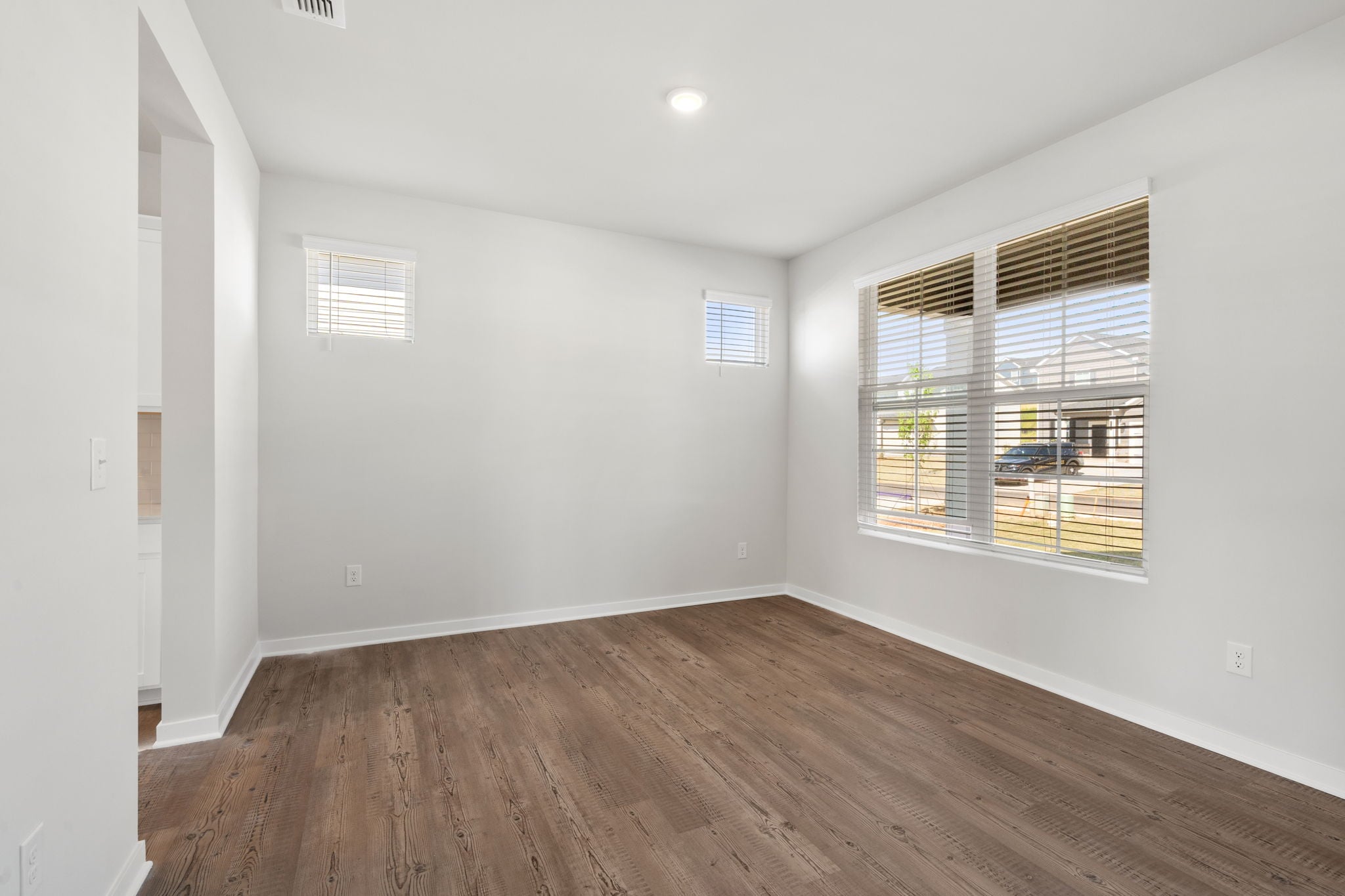 A room with a wood floor and a window with blinds.