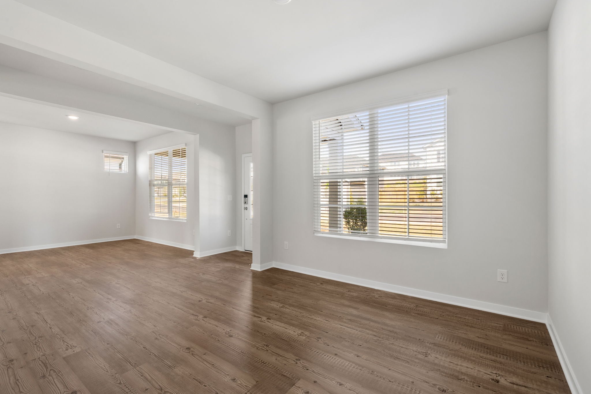 A room with a wood floor and a window with blinds.