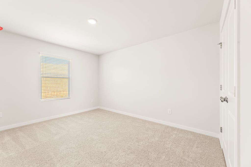 A room with a carpet and a window.