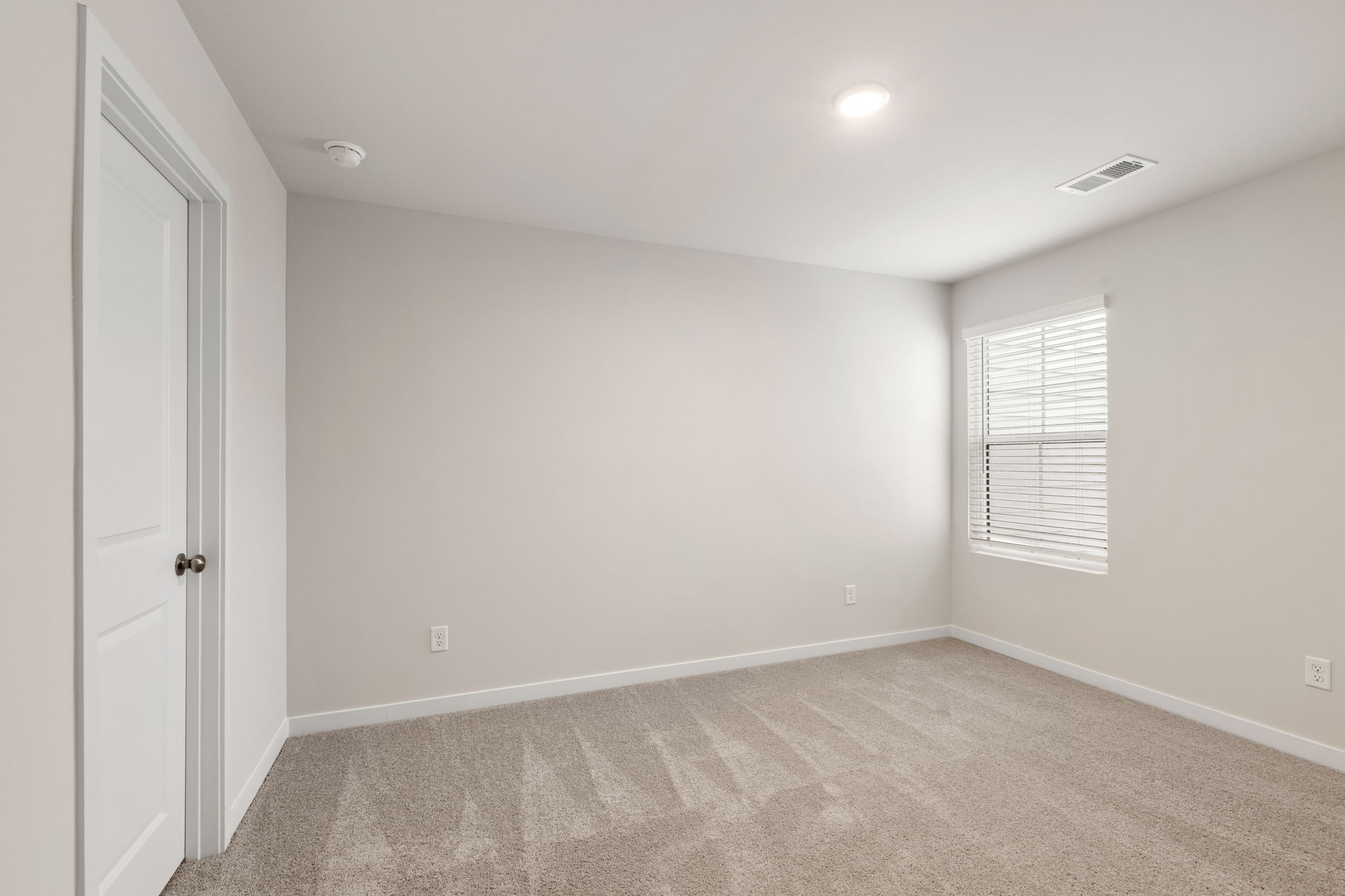 A room with a carpet and a door.