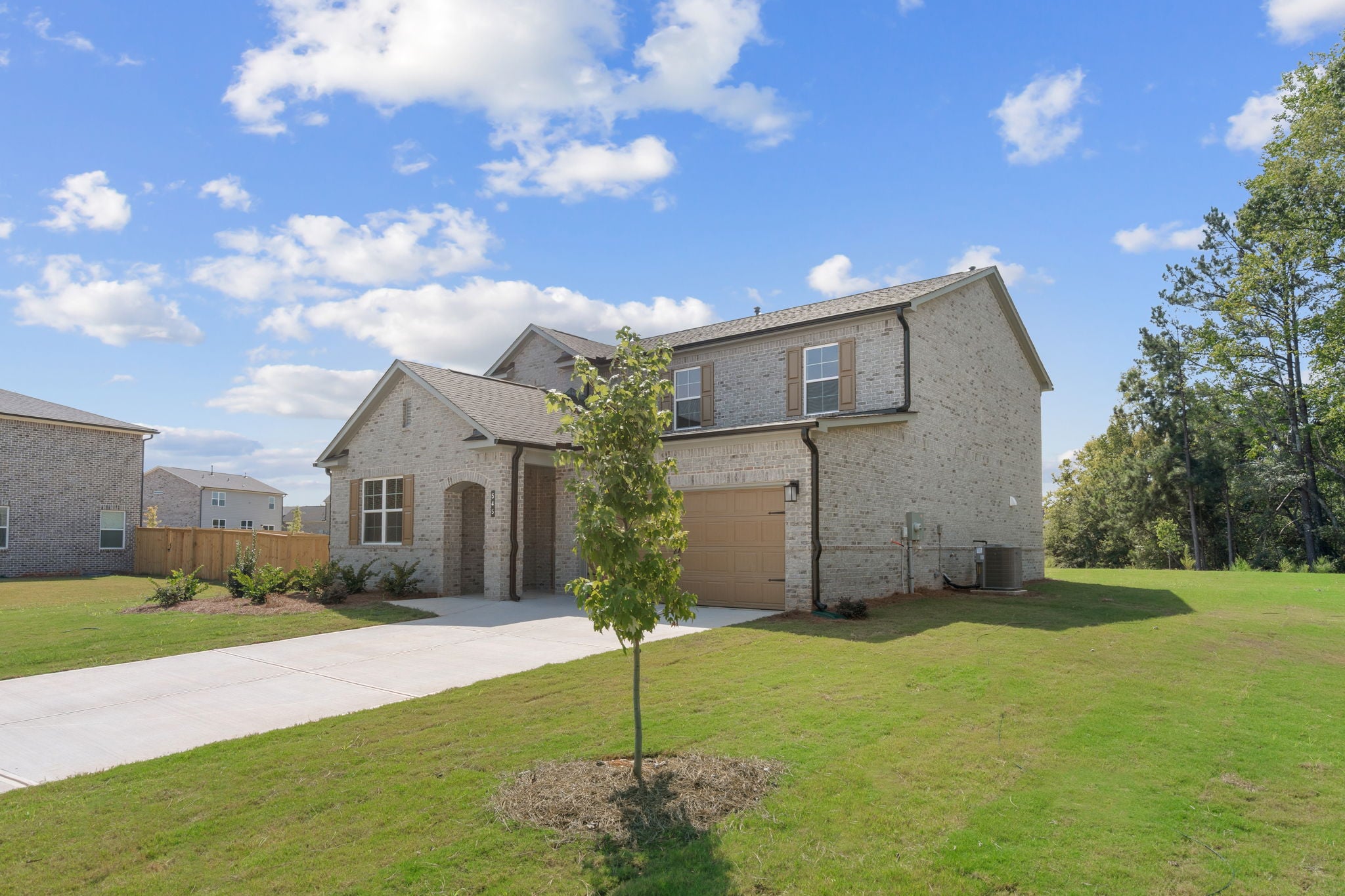 A house with a driveway and a tree in the front.