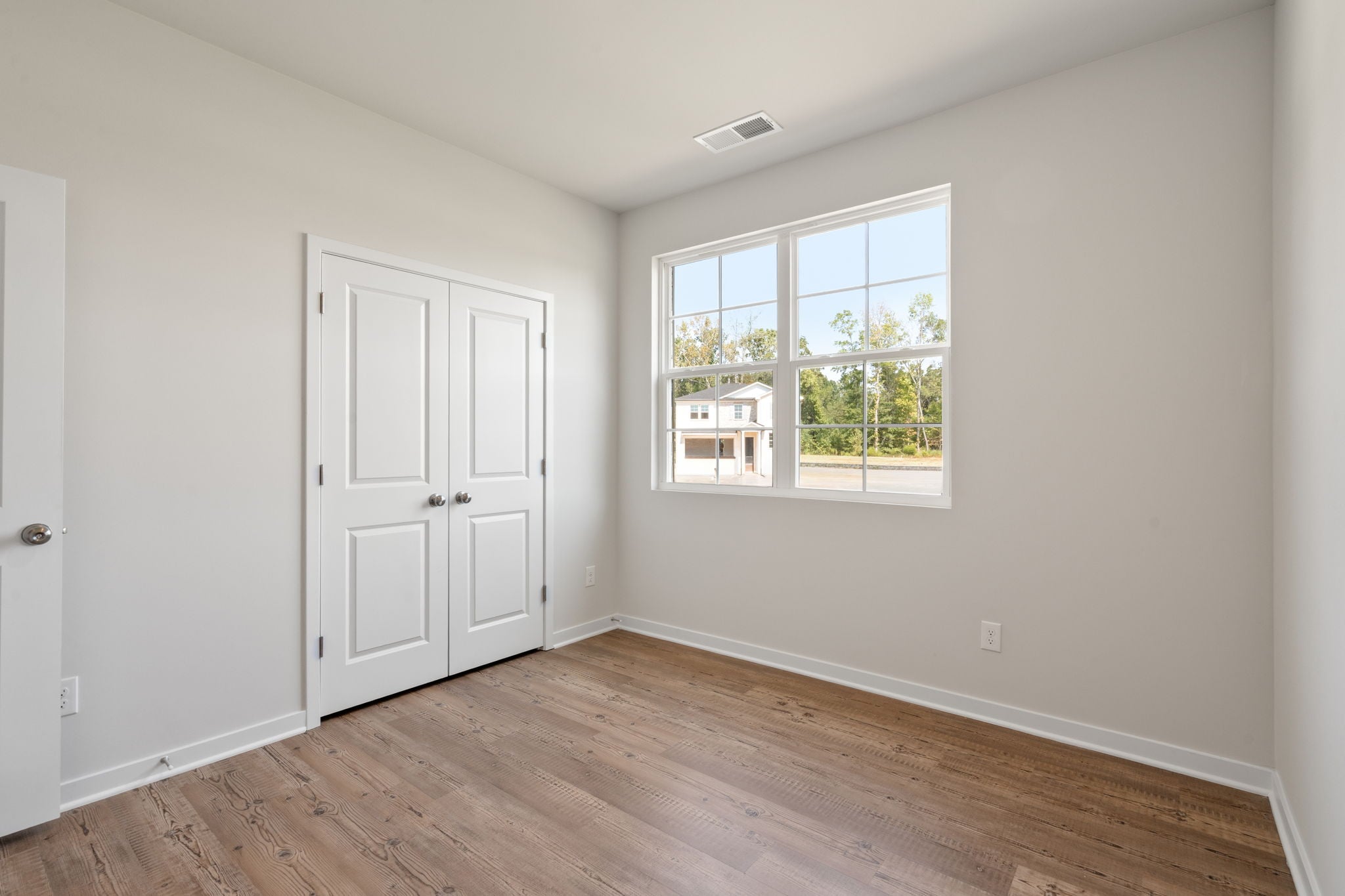 A room with white doors and a wood floor.