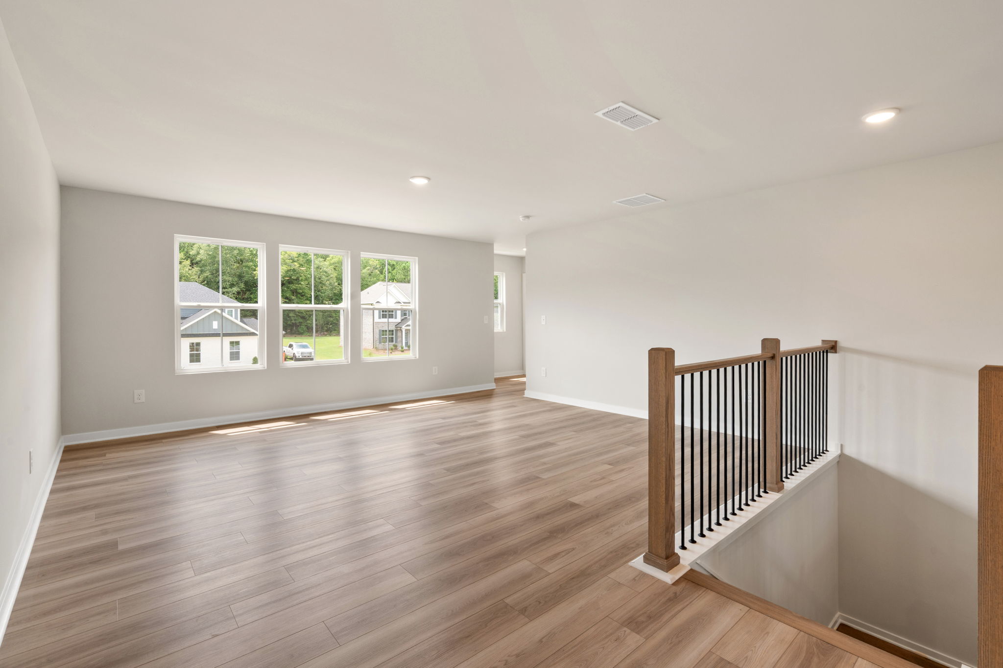 A large empty room with a wood floor and a wood railing.