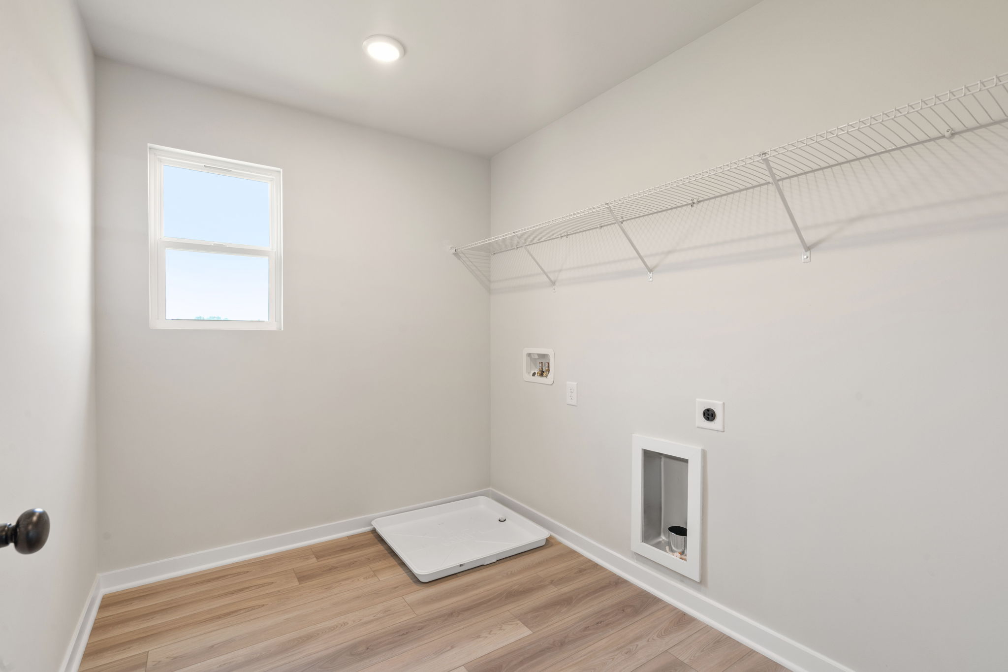 A room with a wood floor and a white wall with a vent.