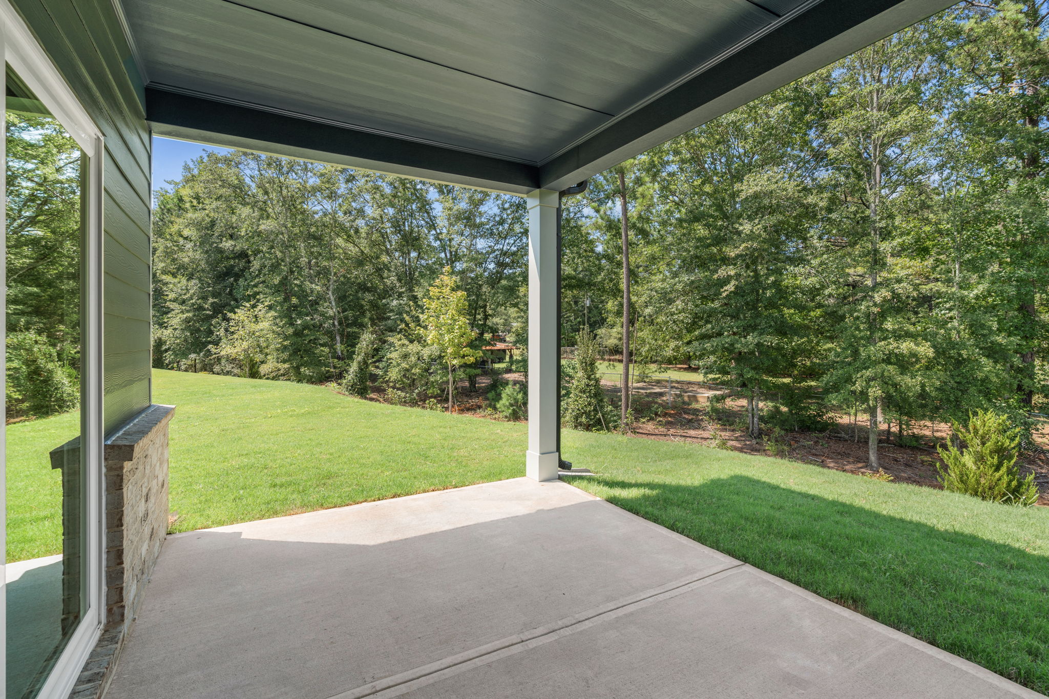 A covered walkway with trees and grass.