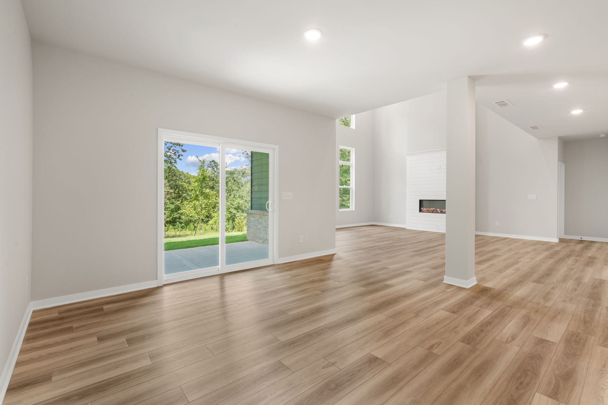 A large empty room with a wood floor and a large glass door.
