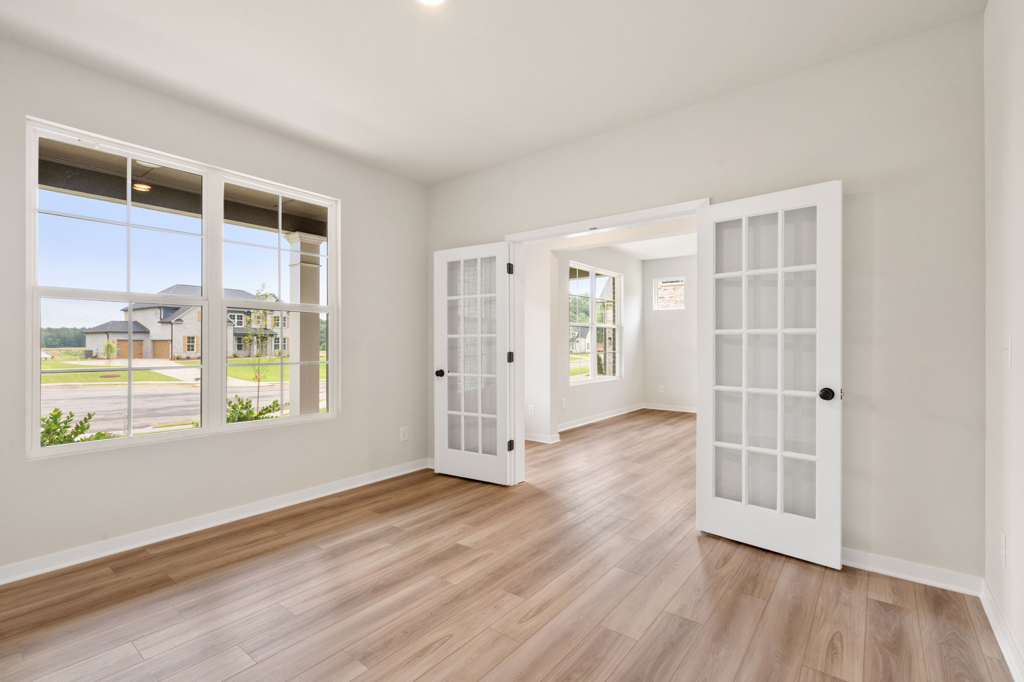 A room with a wood floor and a window with a view of a city.