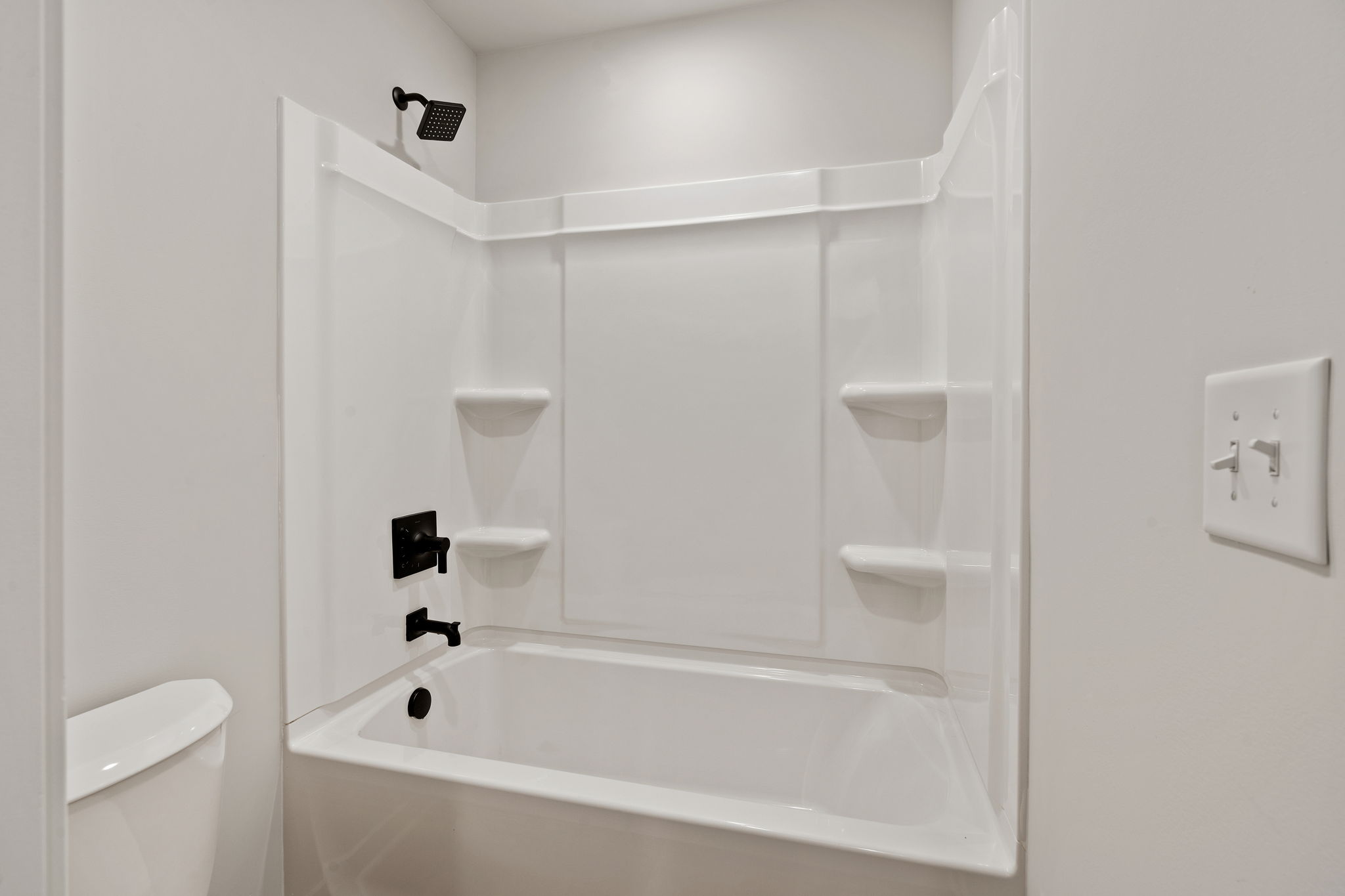 A white bathtub with a glass shower unit.