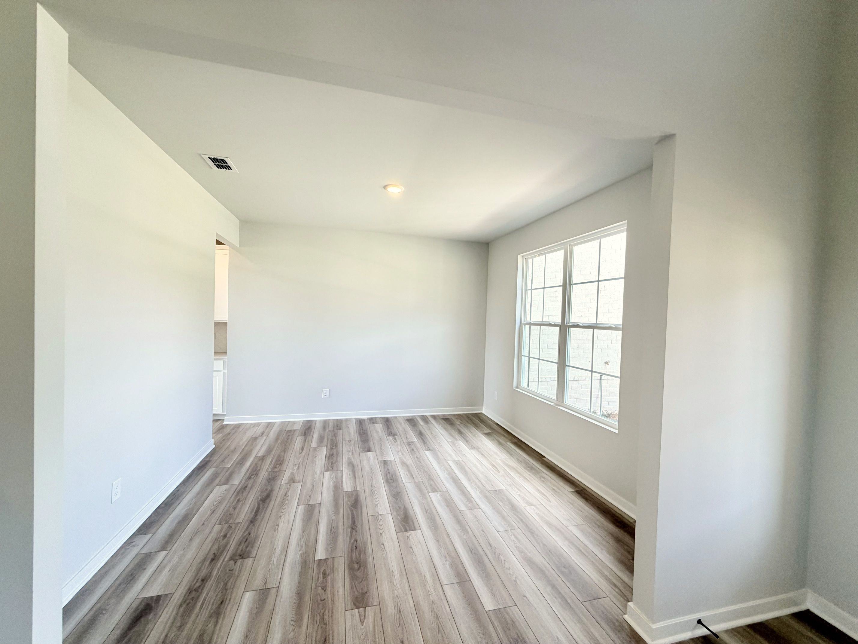 A room with a wood floor and a window.