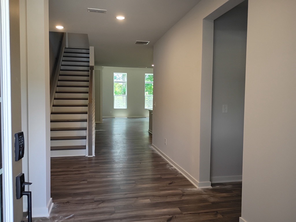 A hallway with a wood floor and white walls.