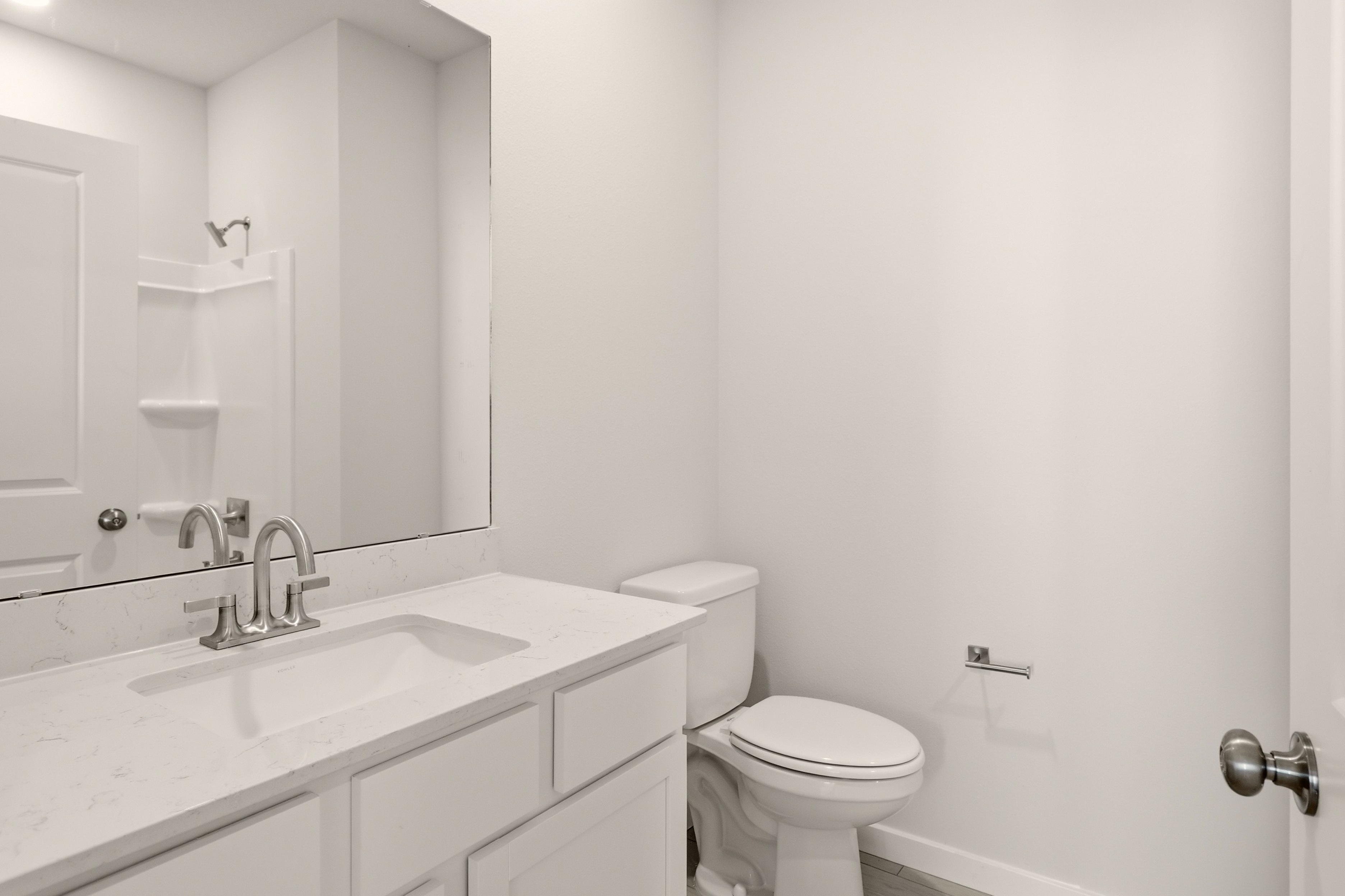 A bathroom with a sink toilet and mirror.