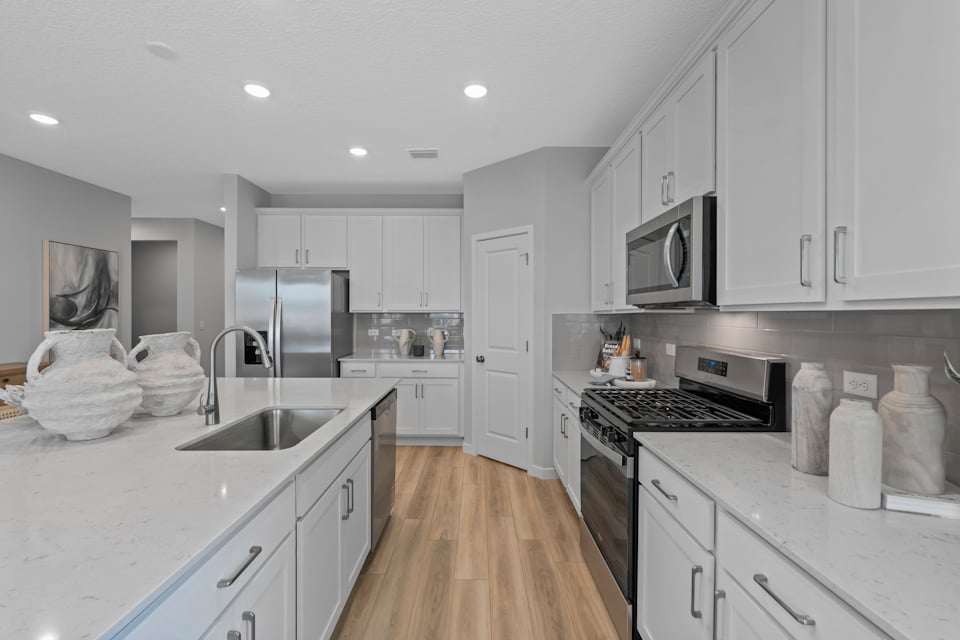 Coronado Model Home Kitchen with White Cabinets and Stainless Steel Appliances at Reserve East in Flagler Beach