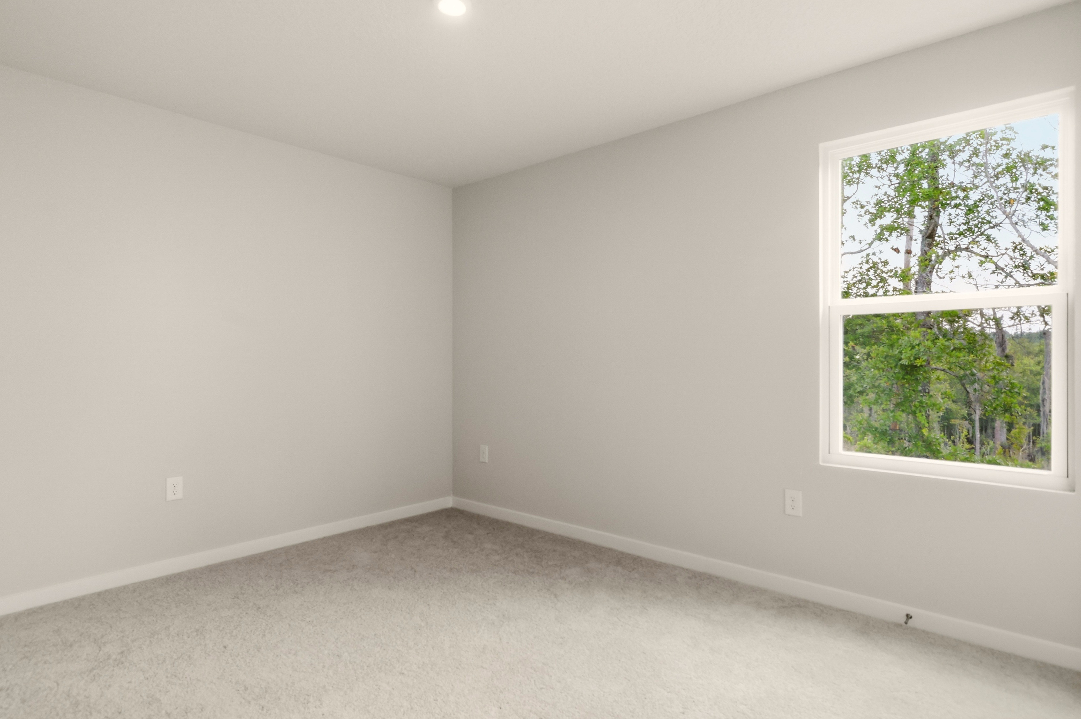 A room with a window and a white wall.