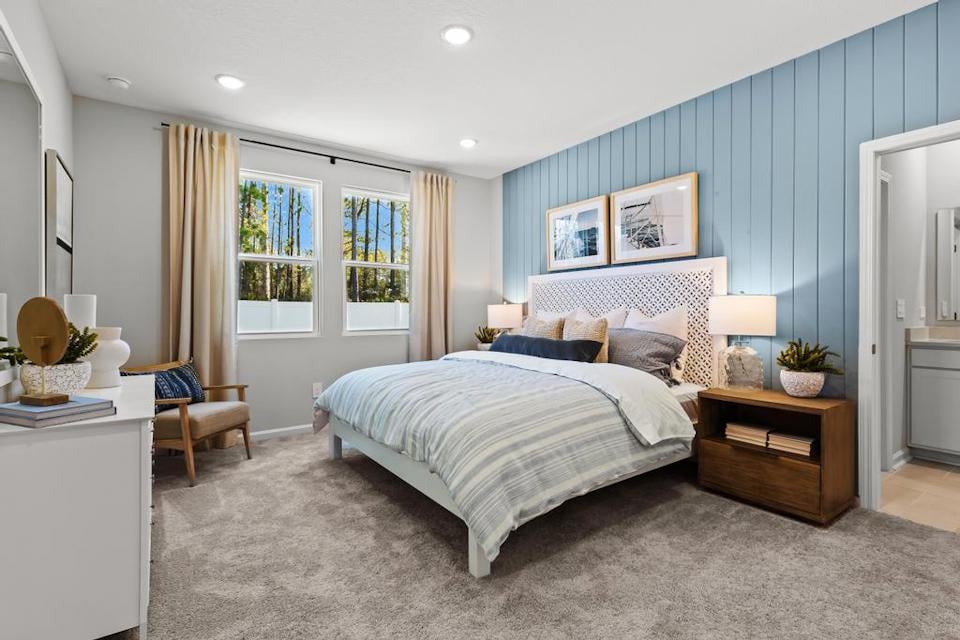 A bedroom with a bed and a chair.