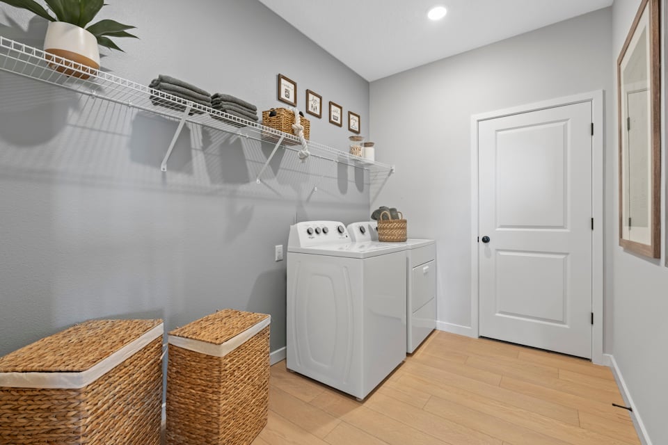 Kenai Model Home Laundry Room with Washer and Dryer and two Basket Hampers at Reserve East in Flagler Beach