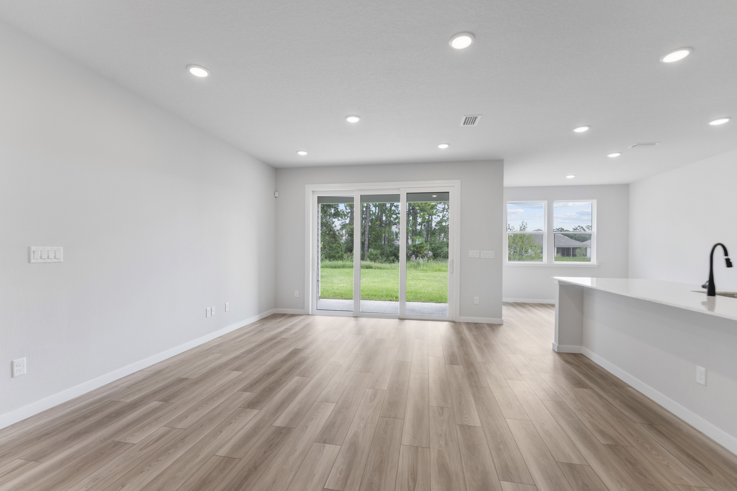 A large room with a wood floor and a large glass door.