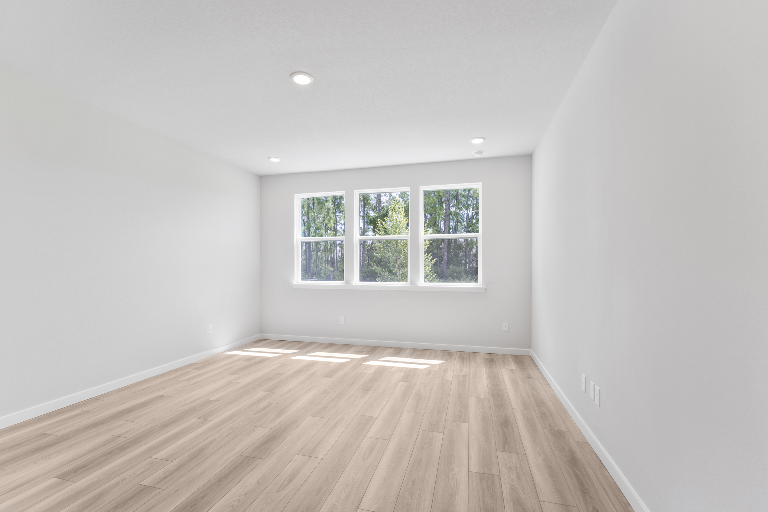 A room with a wood floor and a window with a light on the wall.