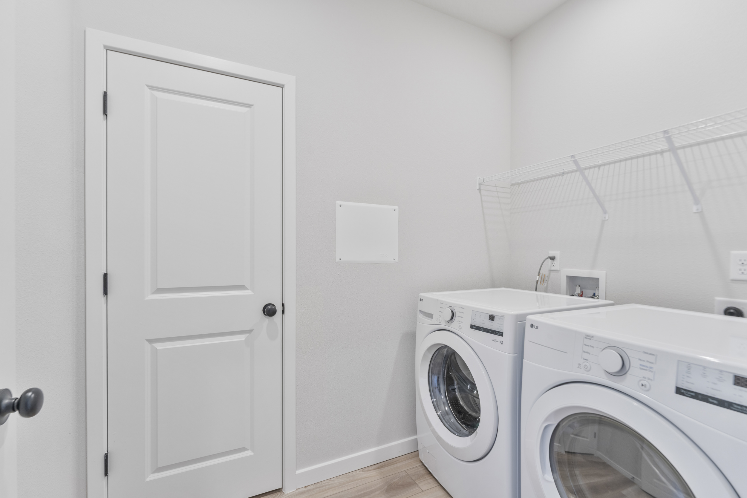 A white laundry room with a white door and a dryer.