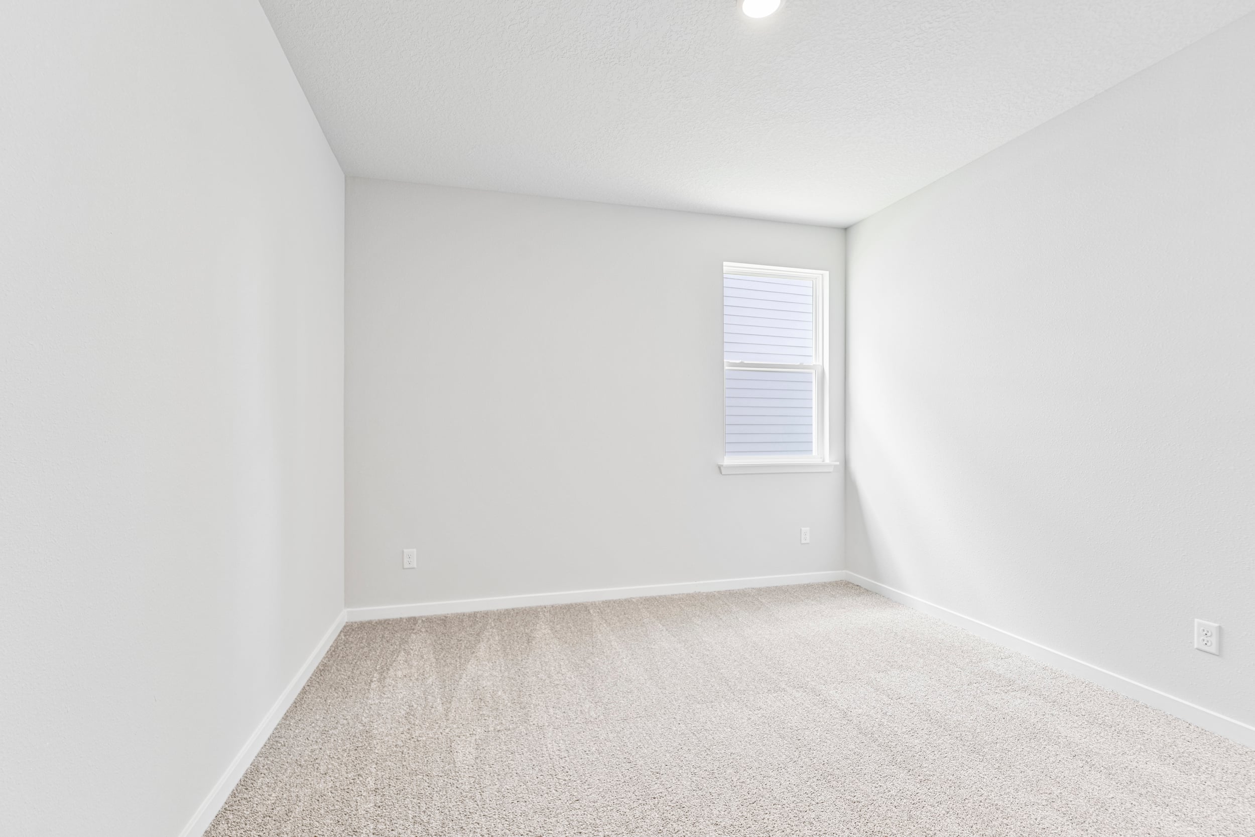 A room with a white wall and a window.
