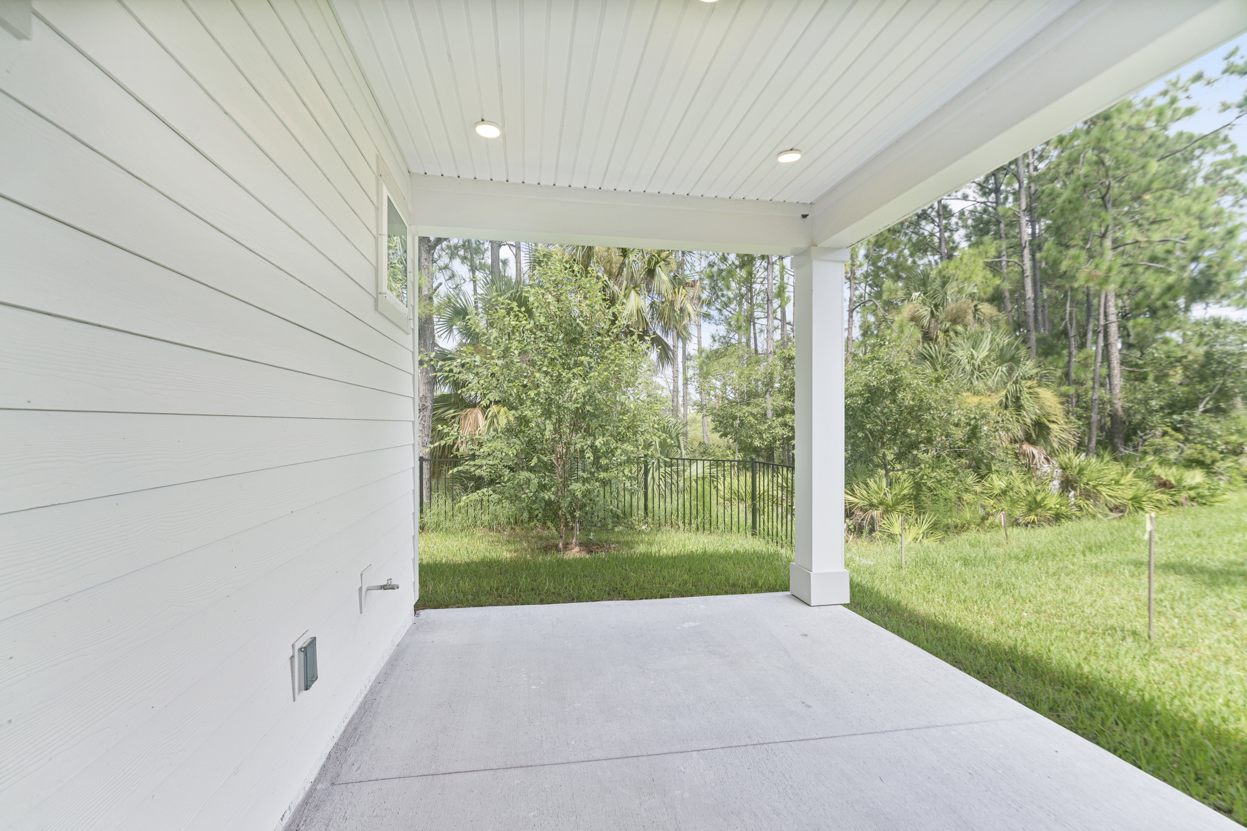 A white building with a walkway and grass and trees.