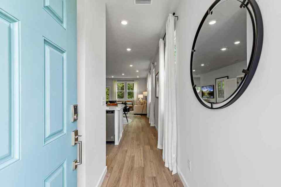 A hallway with a mirror and a desk.