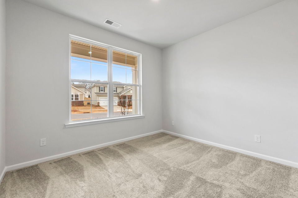 A room with a window and a white wall with a view of a city.