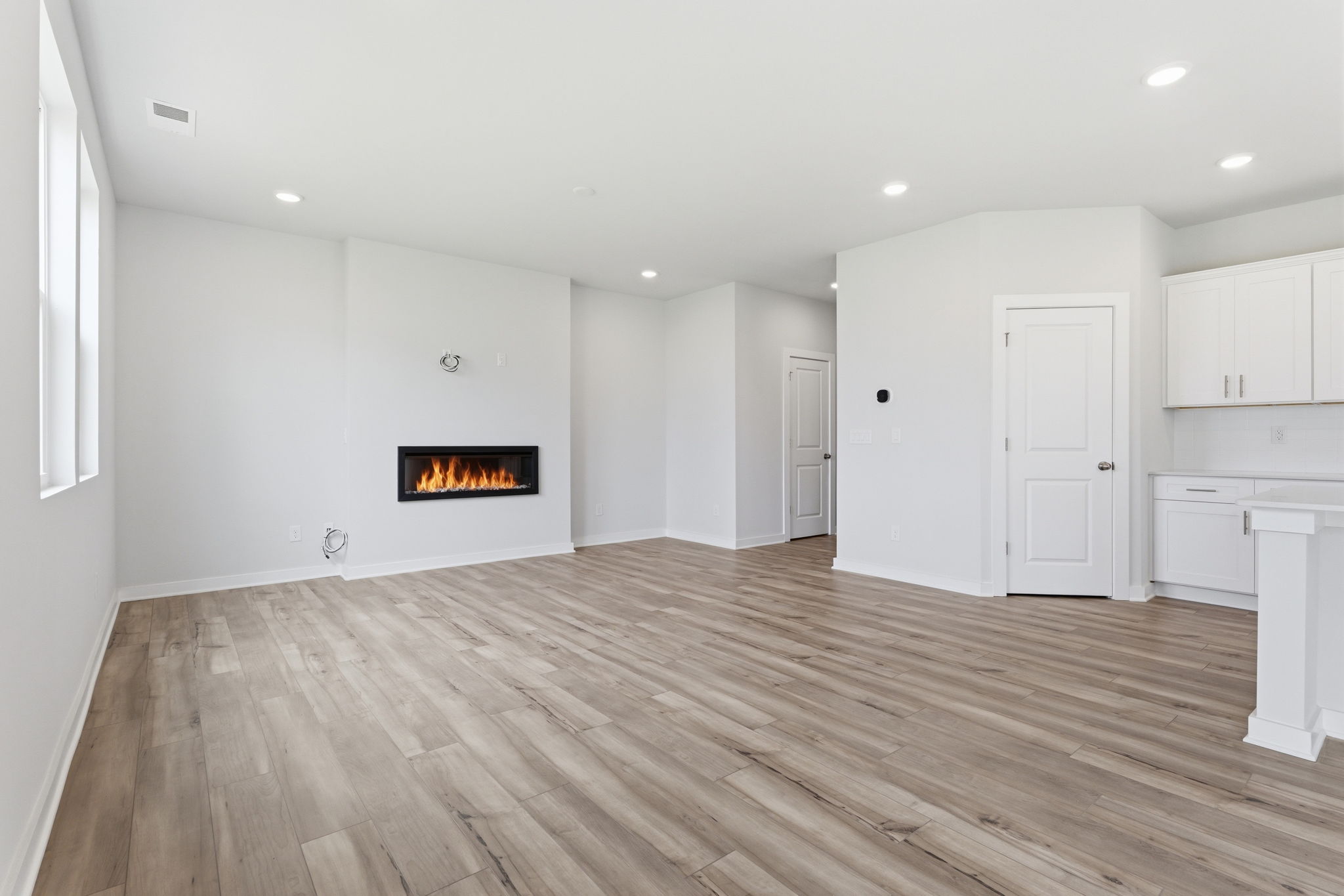 A room with a fireplace and white cabinets.