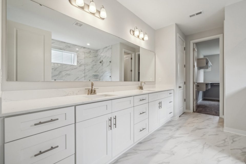 A bathroom with white cabinets.